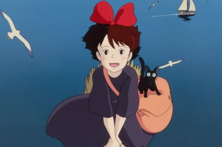 Kiki riding her broomstick, wearing a red bow with cat Jiji by her side perching on a full satchel.